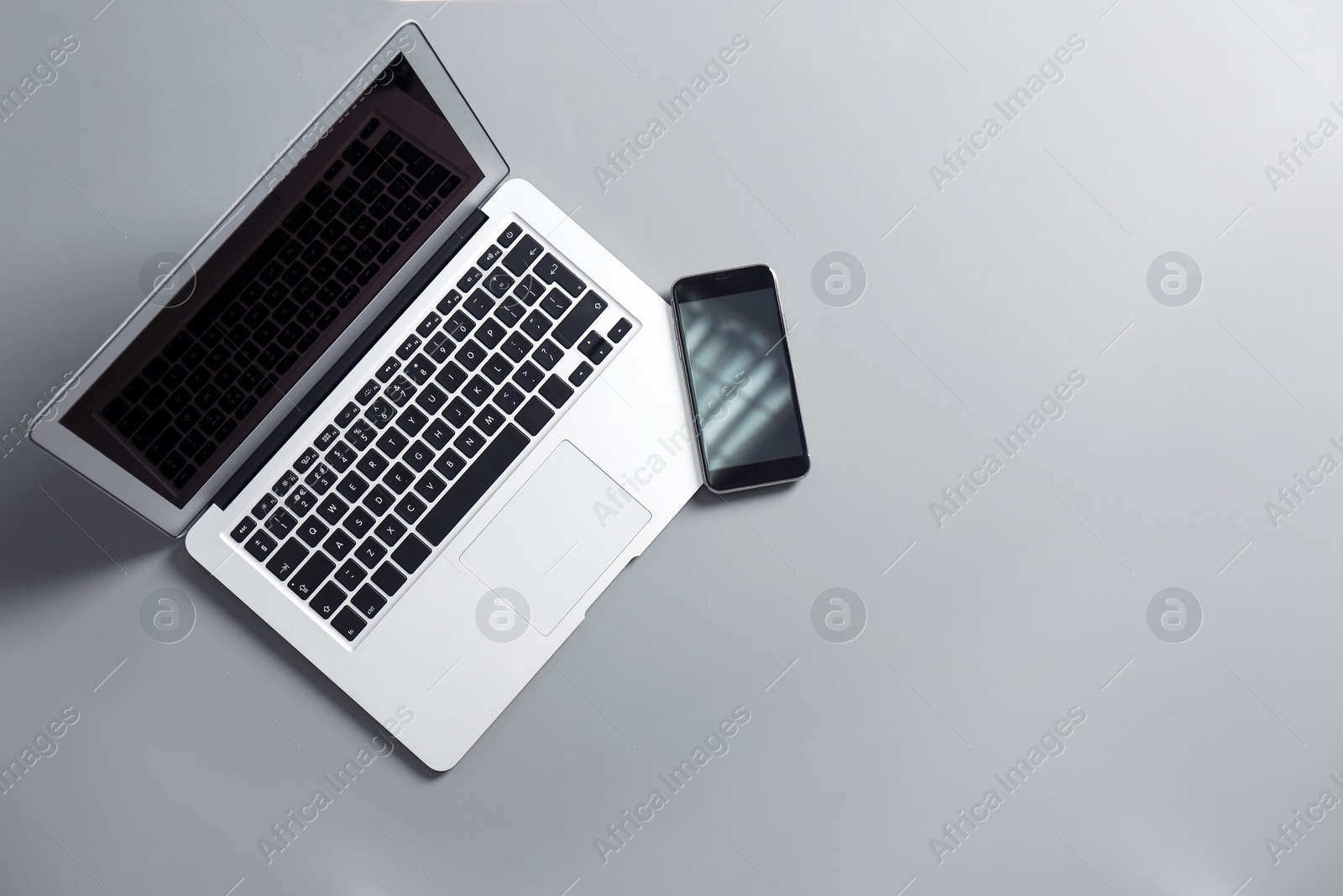 Photo of Modern laptop and mobile phone on gray background, top view