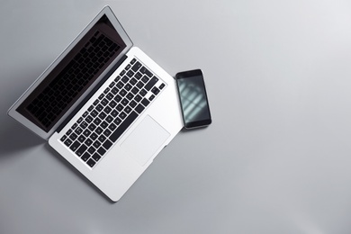 Modern laptop and mobile phone on gray background, top view