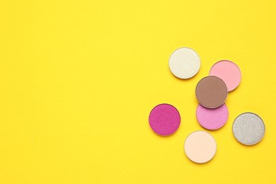 Photo of Beautiful eye shadow refill pans on yellow background, flat lay. Space for text