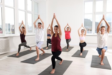 Group of people practicing yoga on mats indoors