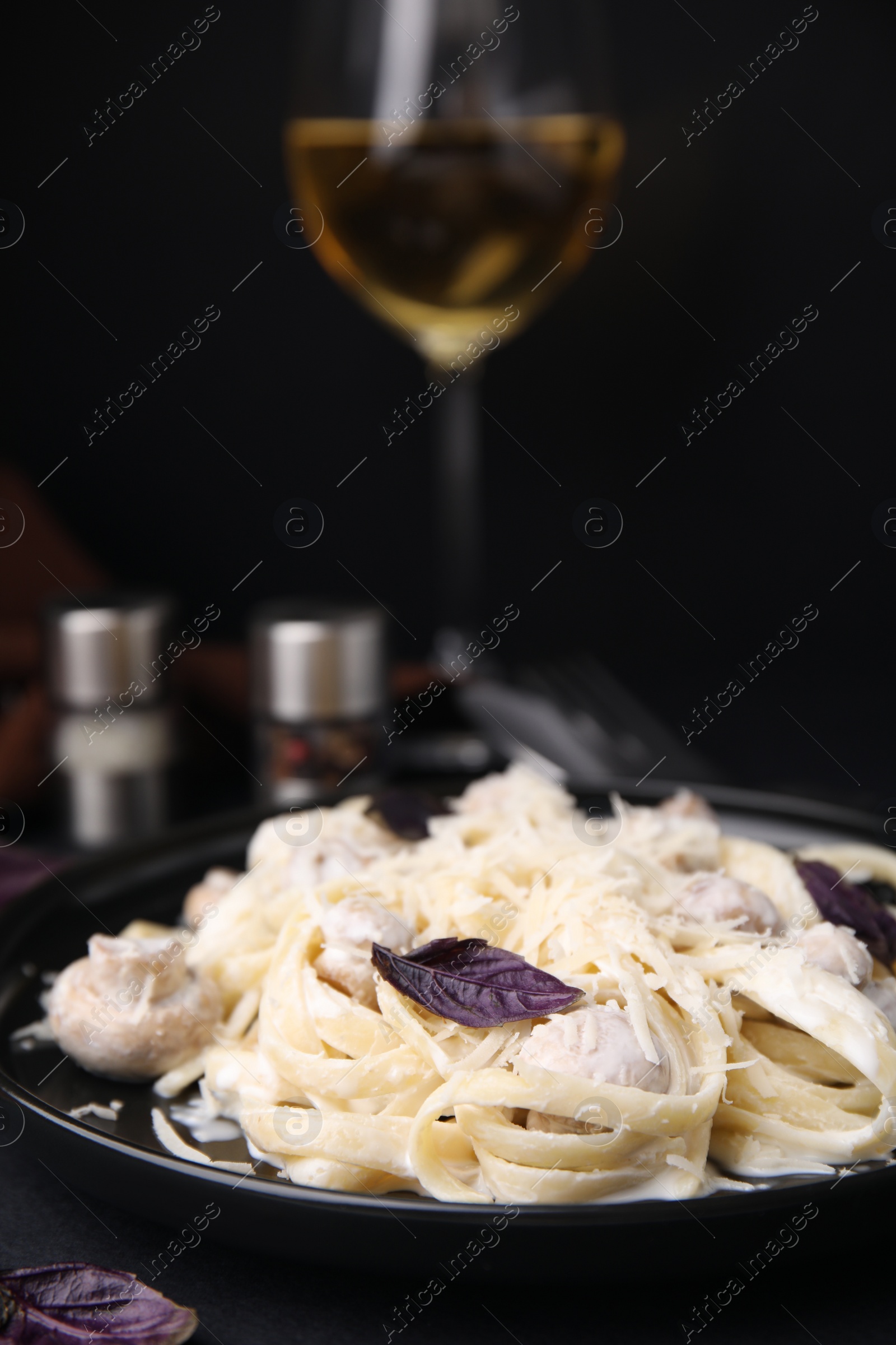 Photo of Delicious pasta with mushrooms on black table, closeup