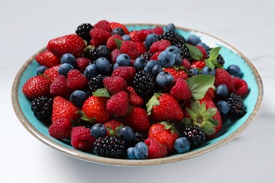 Photo of Many different fresh ripe berries in bowl on white table, closeup