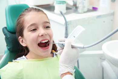 Photo of Professional dentist working with little patient in modern clinic