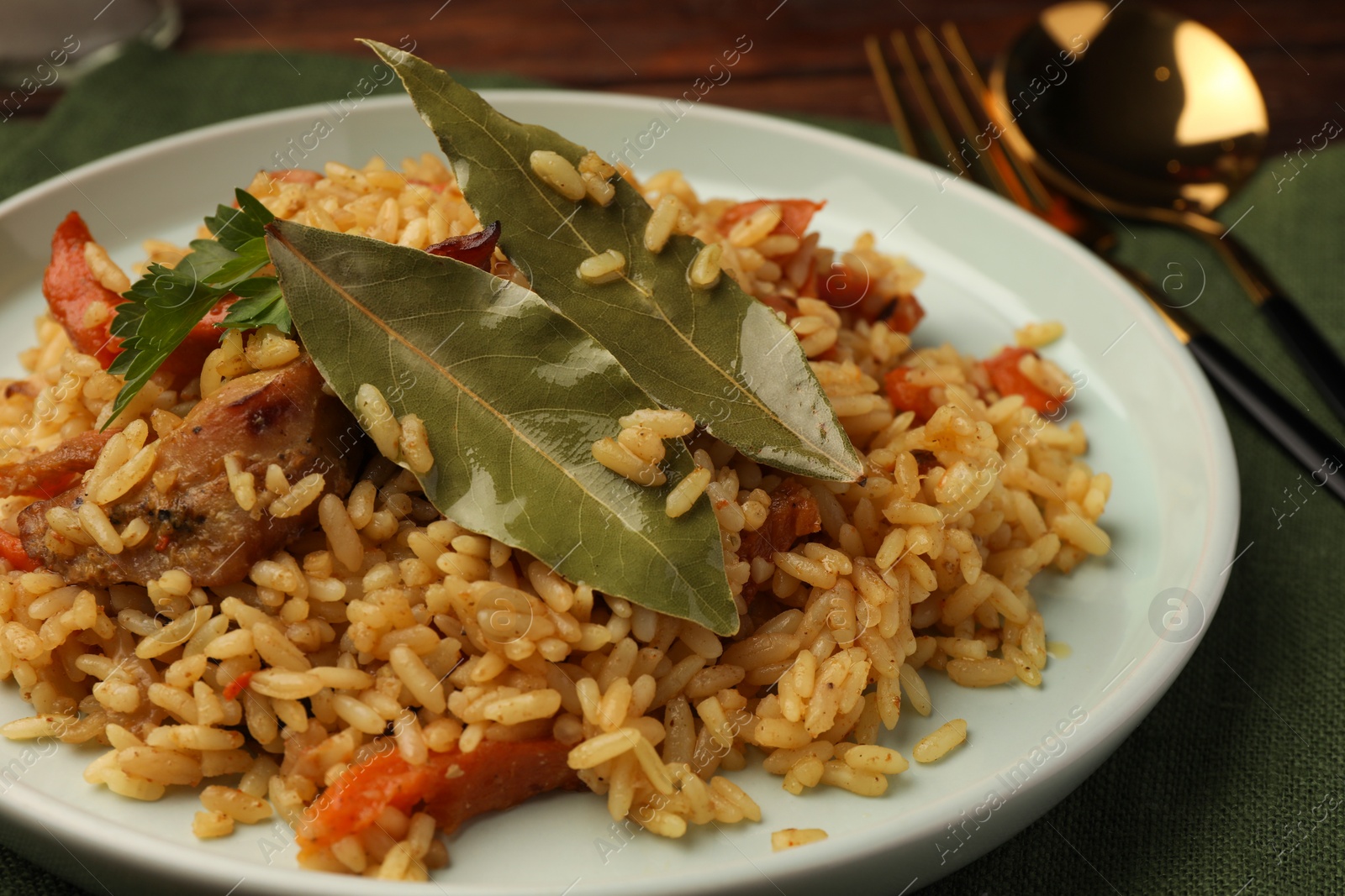 Photo of Delicious pilaf and bay leaves on plate, closeup