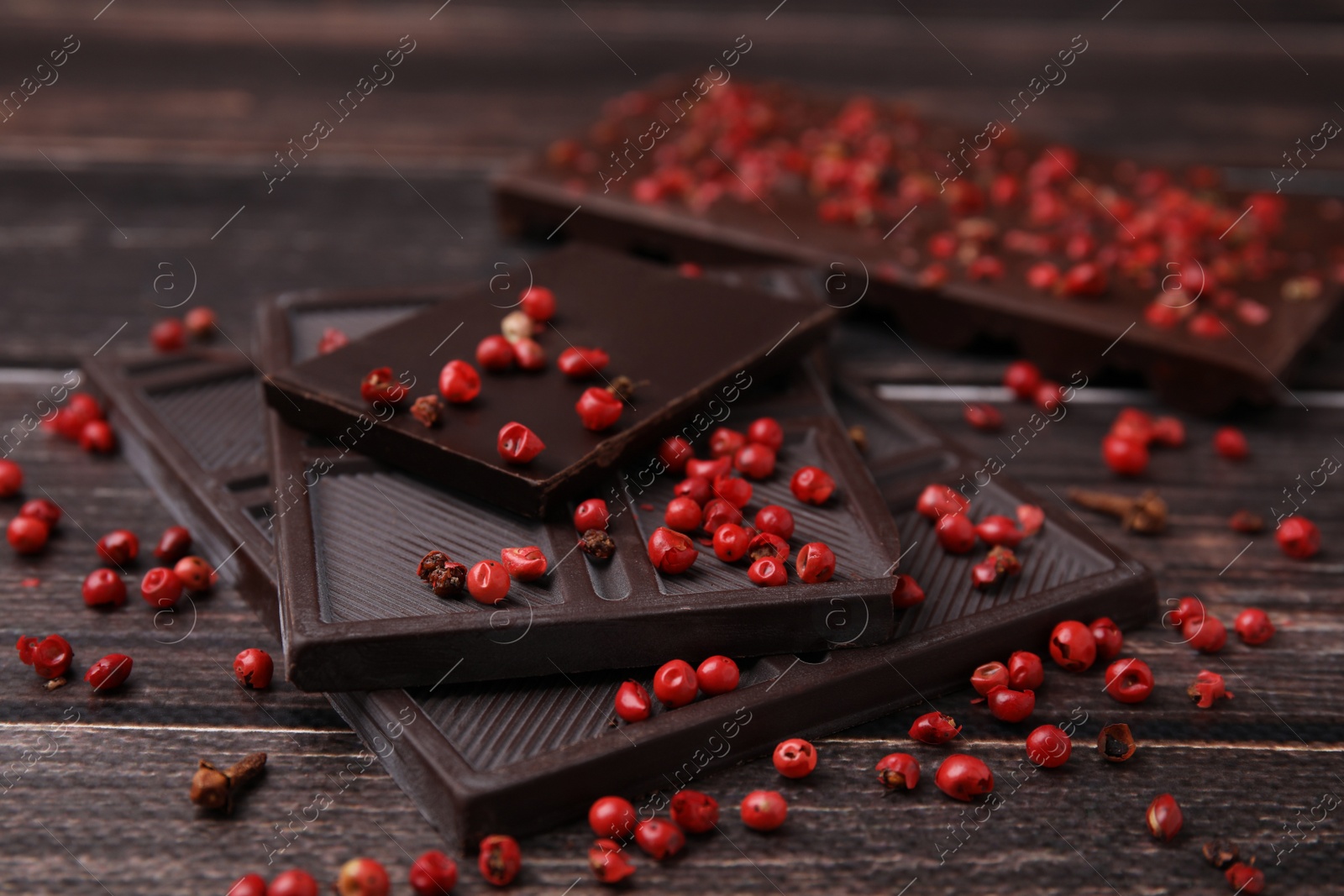 Photo of Delicious chocolate and red peppercorns on wooden table, closeup