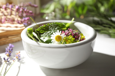 Bowl with healing herbs on white wooden table
