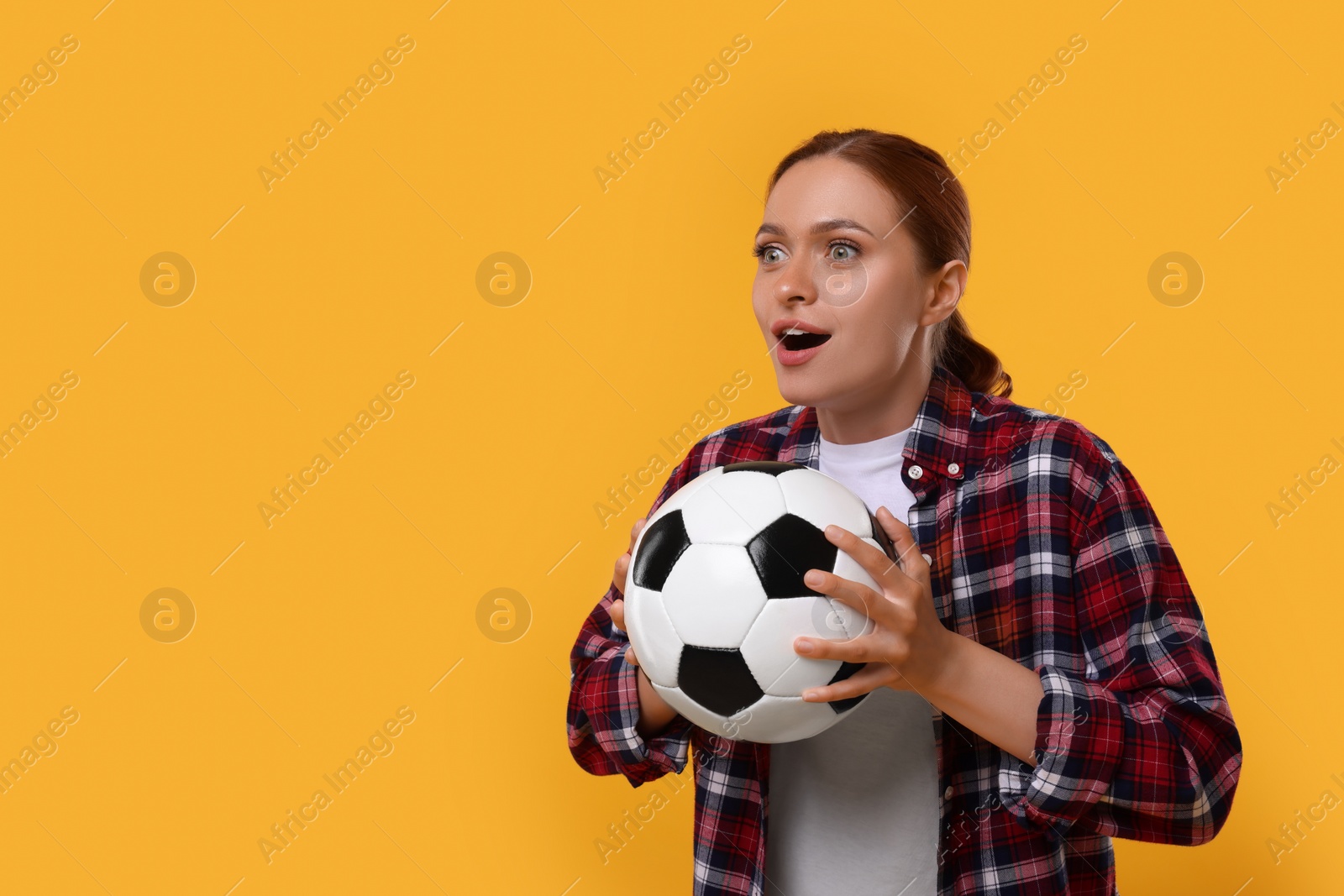 Photo of Emotional fan holding football ball on yellow background, space for text