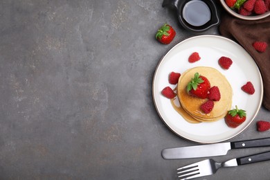 Tasty pancakes served with fresh berries and honey on grey table, flat lay. Space for text