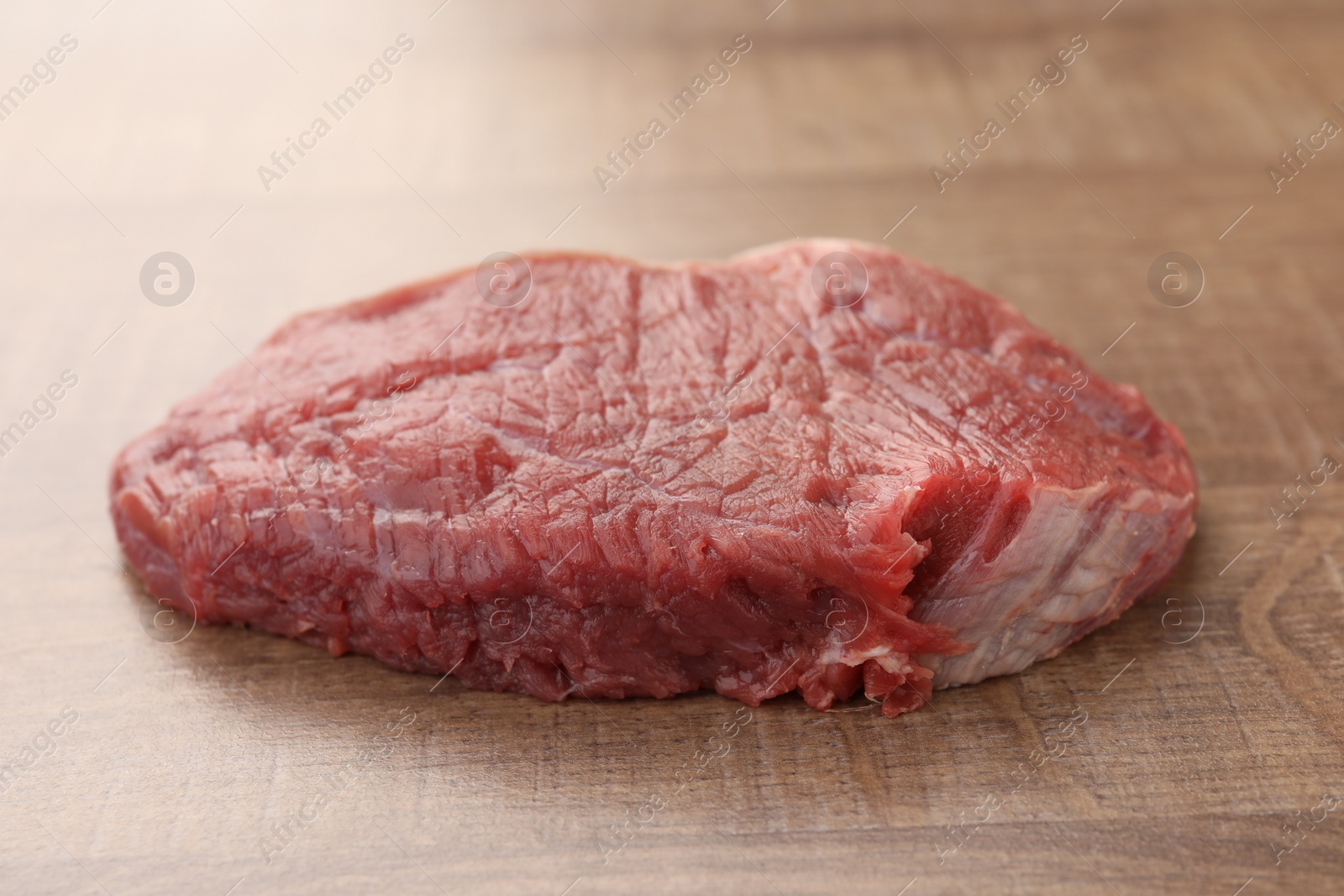 Photo of Piece of raw beef meat on wooden table, closeup