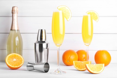 Fresh alcoholic Mimosa cocktails and fresh orange fruits on white wooden table