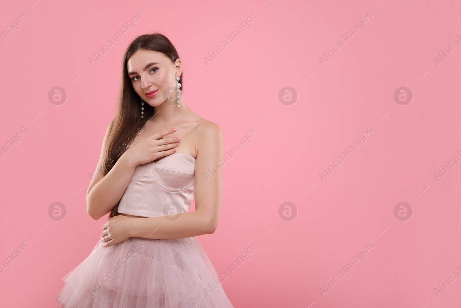 Photo of Beautiful woman in pale pink clothes on color background, space for text