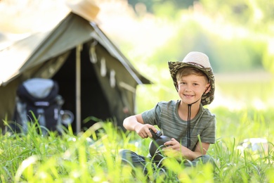 Photo of Little boy with flask near tent outdoors. Summer camp
