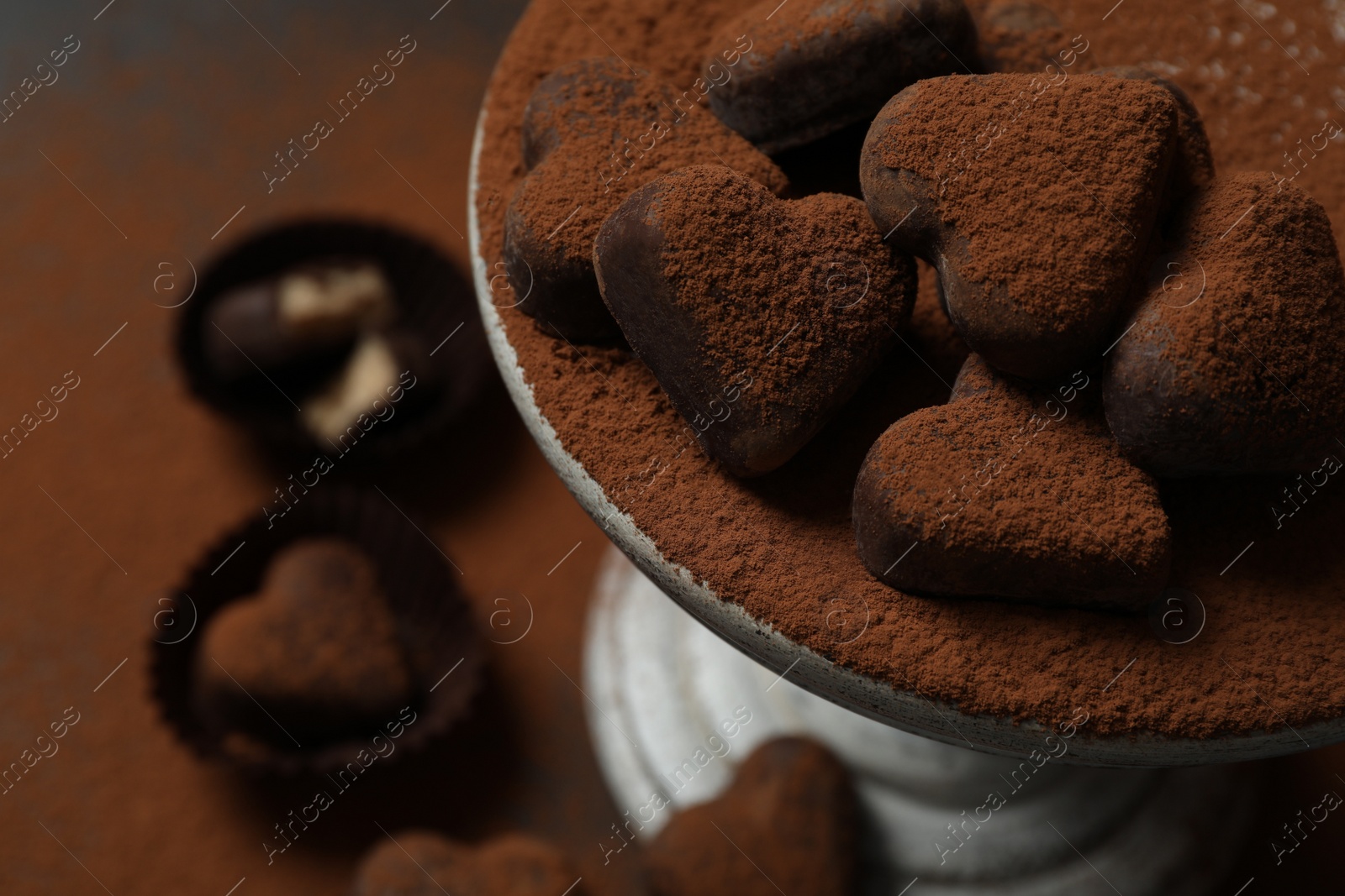 Photo of Beautiful heart shaped chocolate candies on dessert stand. Space for text