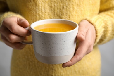 Photo of Woman holding cup with sea buckthorn tea, closeup view