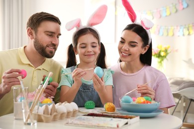 Photo of Happy family painting Easter eggs at table indoors