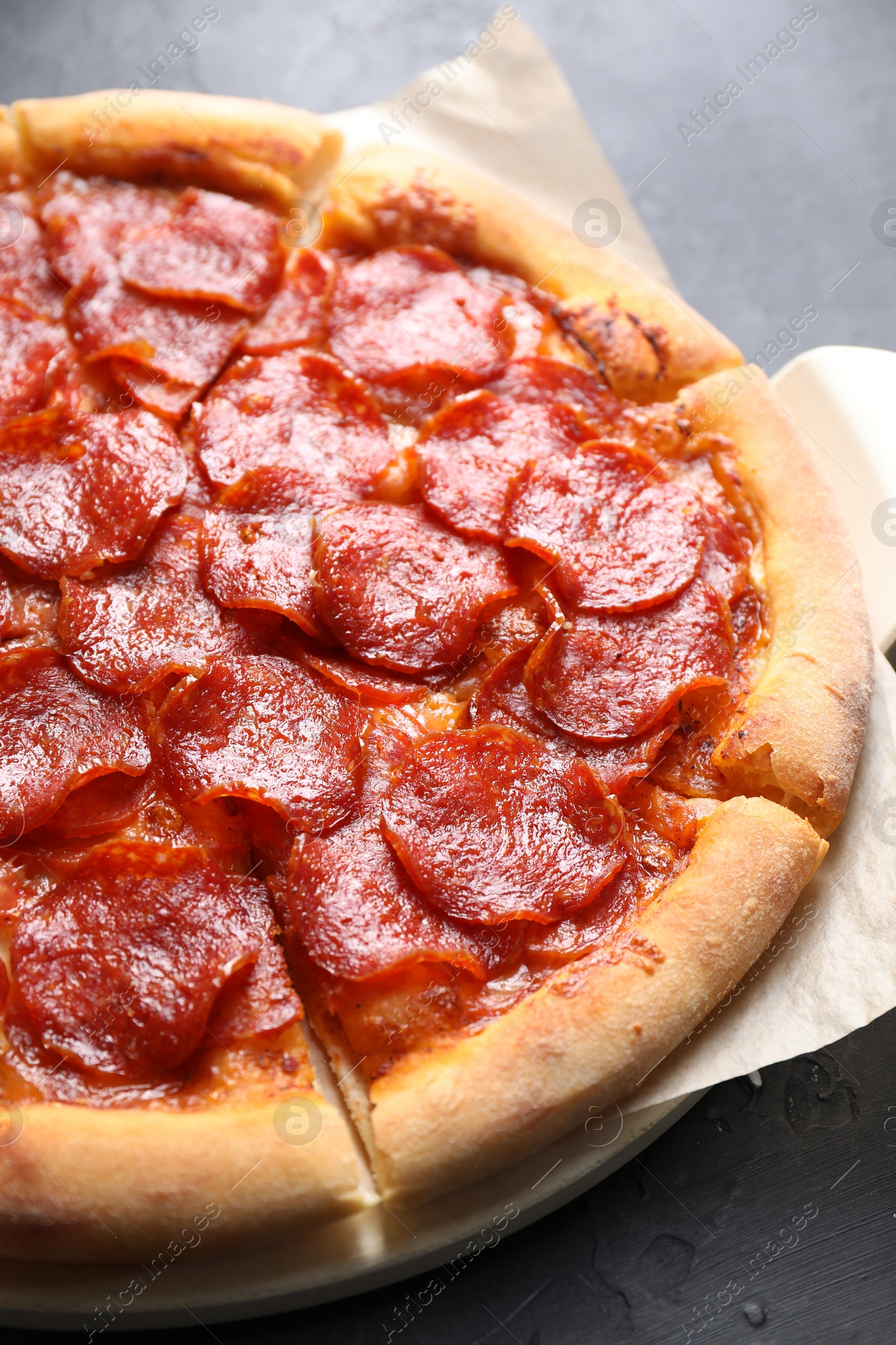 Photo of Tasty pepperoni pizza on dark grey table, closeup