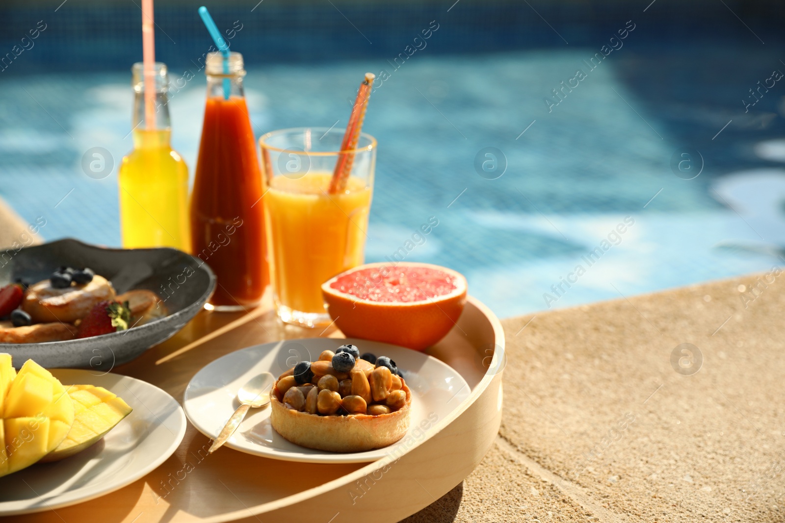 Photo of Tray with delicious breakfast near swimming pool, closeup. Space for text