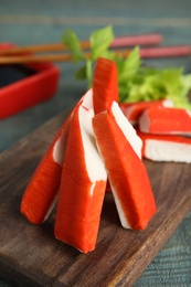Photo of Fresh crab sticks served on wooden board, closeup