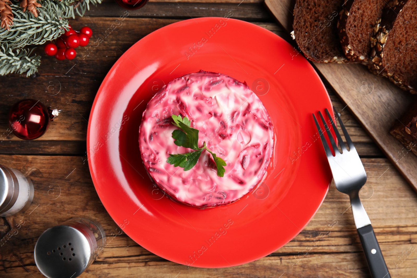 Photo of Herring under fur coat served on wooden table, flat lay. Traditional russian salad