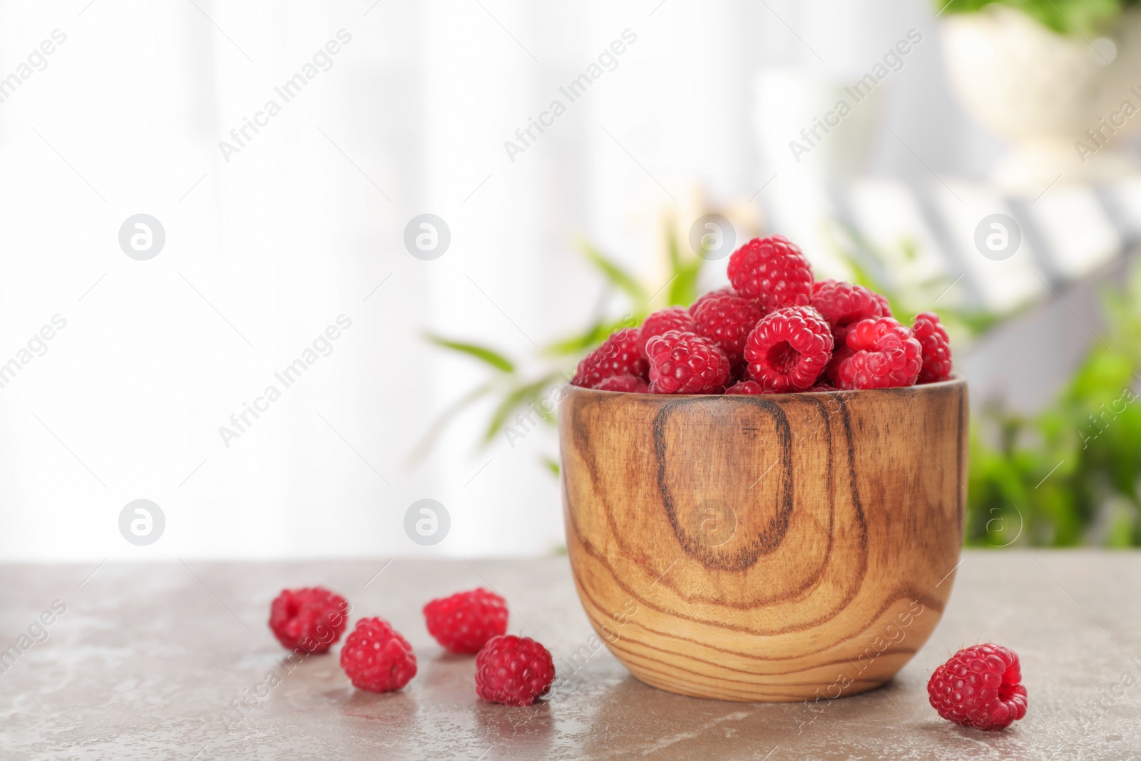 Photo of Bowl with ripe aromatic raspberries on table