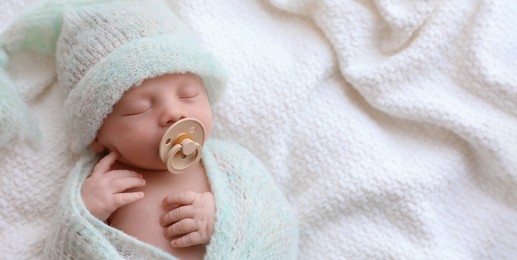 Cute newborn baby in warm hat sleeping on white plaid, top view with space for text. Banner design