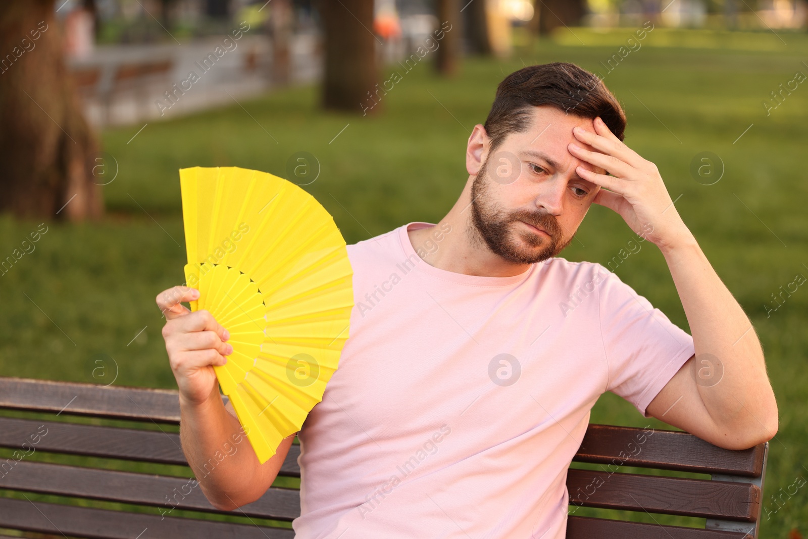 Photo of Man with hand fan suffering from heat outdoors