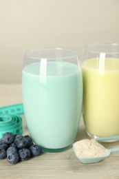 Photo of Tasty shakes, blueberries and powder on wooden table, closeup. Weight loss
