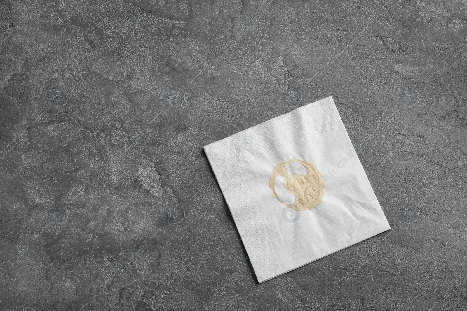 Photo of Dirty napkin with coffee stain on grey background, top view. Space for text