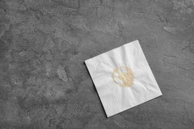 Photo of Dirty napkin with coffee stain on grey background, top view. Space for text