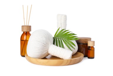 Wooden tray with herbal massage bags and different spa products on white background