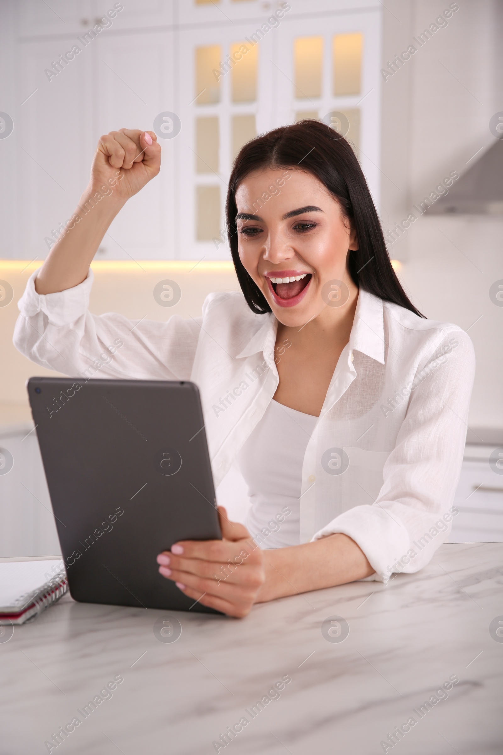 Photo of Emotional woman participating in online auction using tablet at home