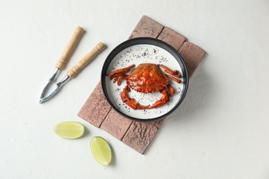 Photo of Delicious boiled crab with cream sauce and lime served on white table, flat lay
