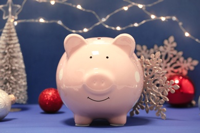 Composition with piggy bank and Christmas decor on color background