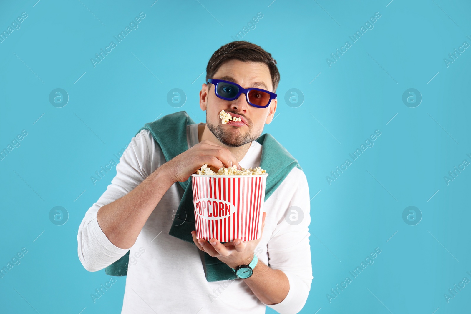 Photo of Man with 3D glasses eating tasty popcorn on color background