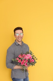 Male florist holding bouquet of beautiful flowers on color background