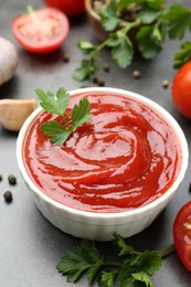 Photo of Delicious tomato ketchup and parsley in bowl on grey table, closeup