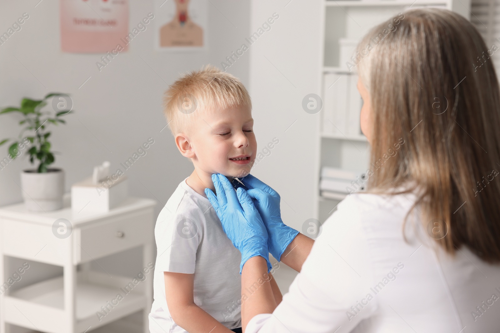 Photo of Endocrinologist examining boy's thyroid gland at hospital