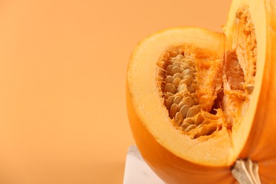 Photo of Cut fresh ripe pumpkin on pale orange background, closeup. Space for text