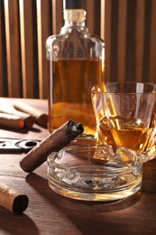 Photo of Cigars, ashtray and whiskey on wooden table