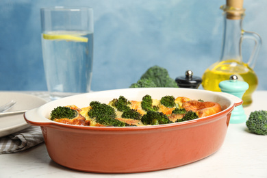 Photo of Tasty broccoli casserole in baking dish on white wooden table