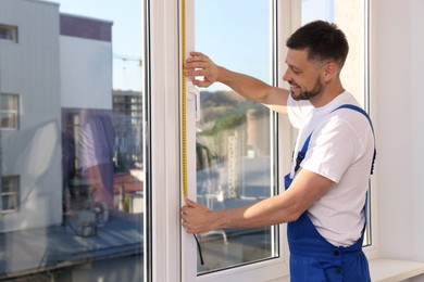 Photo of Worker measuring plastic window indoors. Installation process