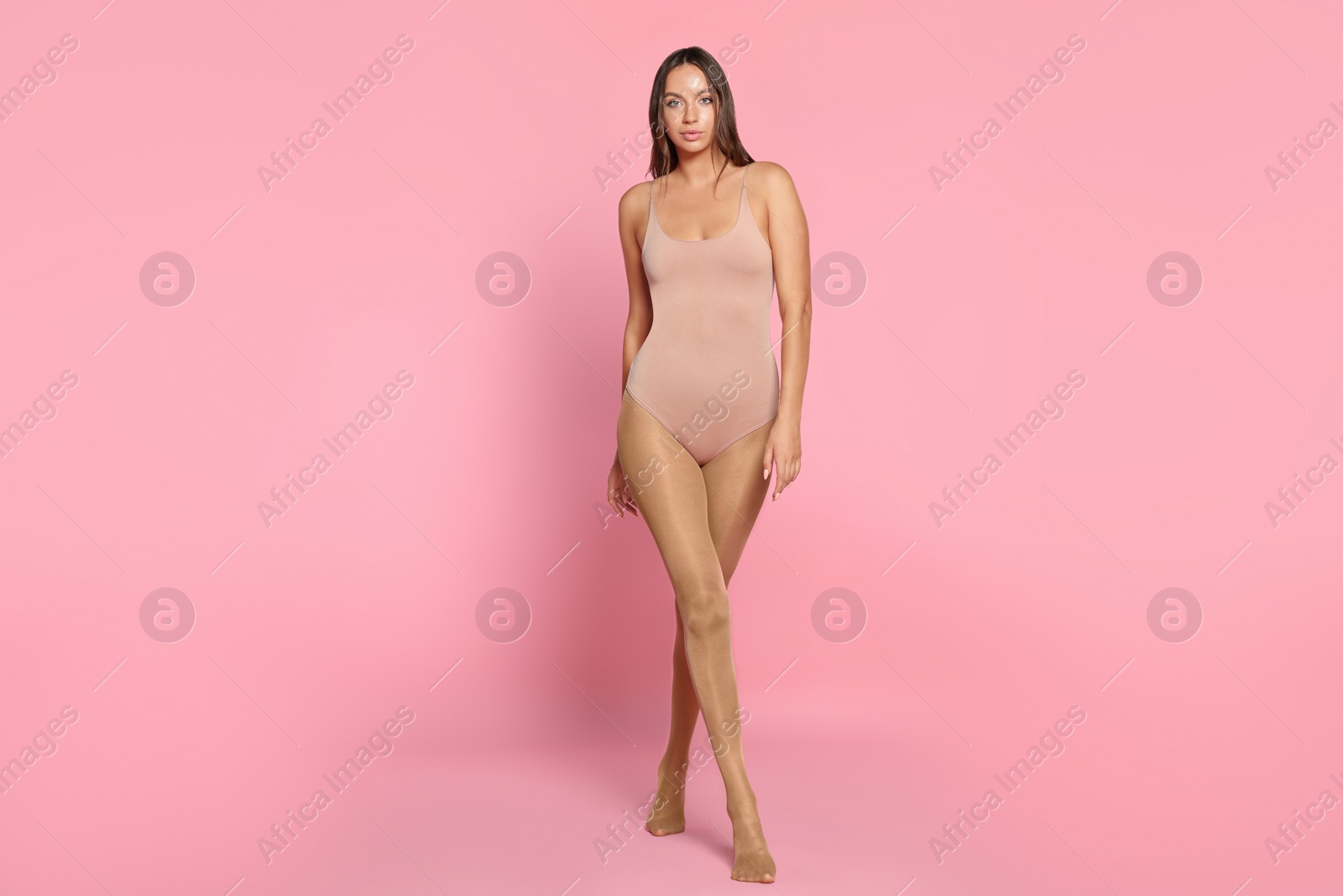 Photo of Beautiful woman wearing tights and bodysuit on pink background