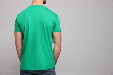 Photo of Man wearing green t-shirt on light grey background, back view. Mockup for design