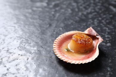 Photo of Delicious fried scallop in shell on black table. Space for text