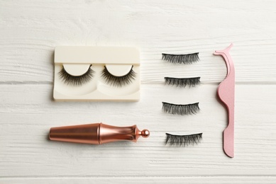 Photo of Flat lay composition with magnetic eyelashes and accessories on white wooden table