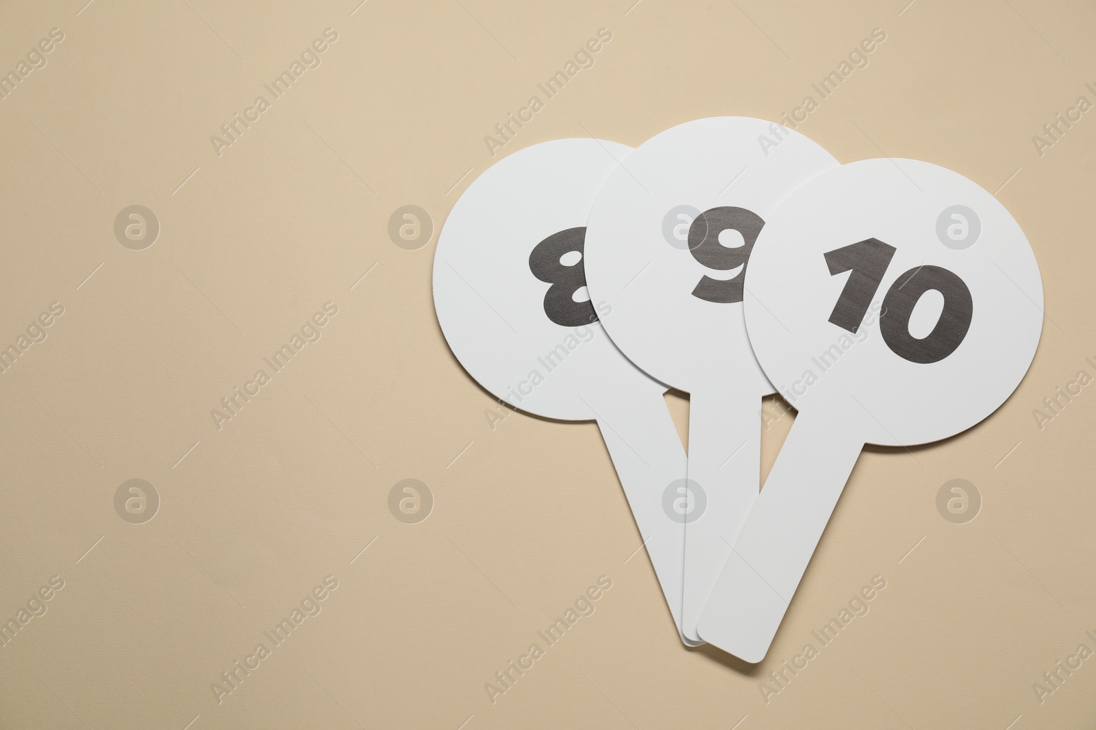 Photo of Auction paddles with numbers on beige background, flat lay. Space for text