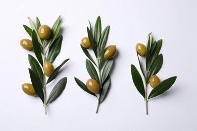 Photo of Twigs with olives and fresh green leaves on white background, flat lay