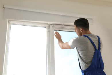 Professional worker tinting window with foil indoors. Space for text