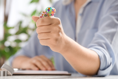 Photo of Woman squeezing colorful slime in office, closeup. Antistress toy