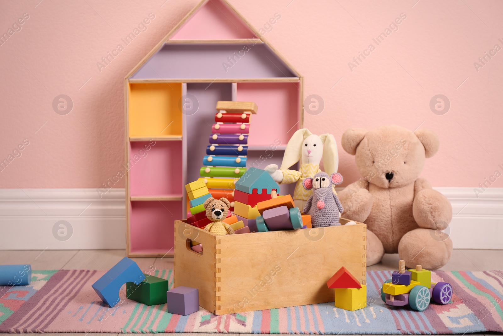 Photo of Set of different cute toys on floor near pink wall